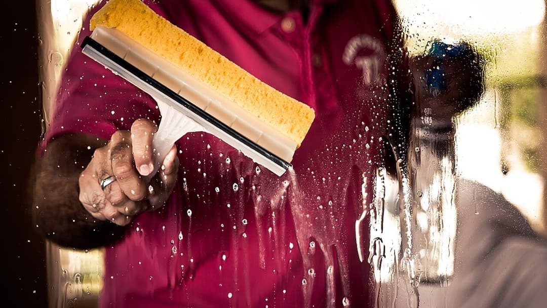 Person wearing rubber gloves washing exterior house windows