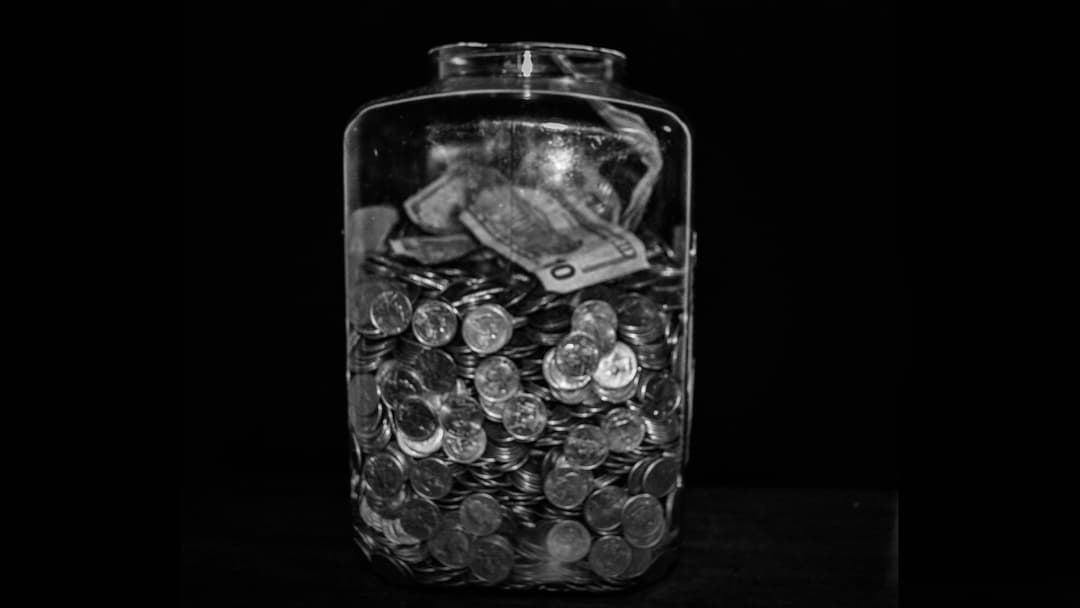 Glass tip jar filled with US dollar banknotes sitting on a customer service counter.