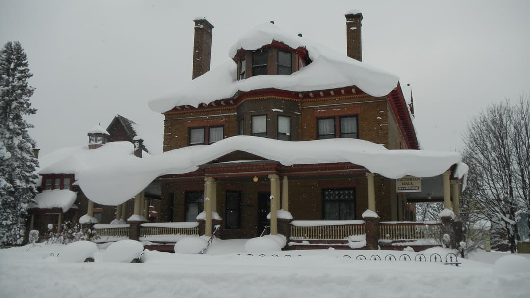 Victorian house buried in deep winter snow in Michigan