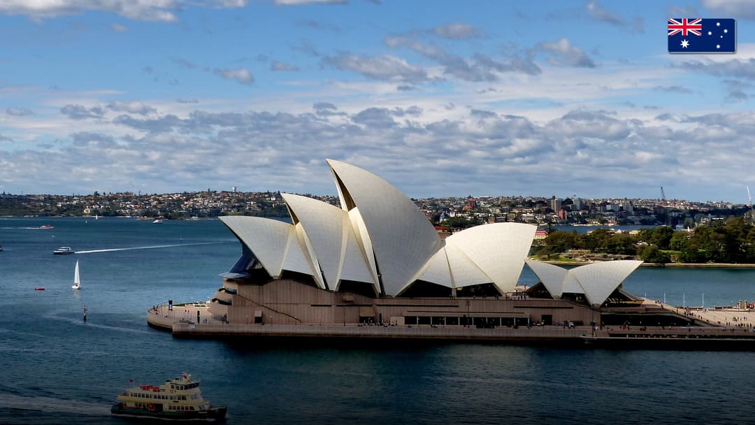 The gleaming white architectural sails of the Sydney Opera House overlooking Sydney Harbour.