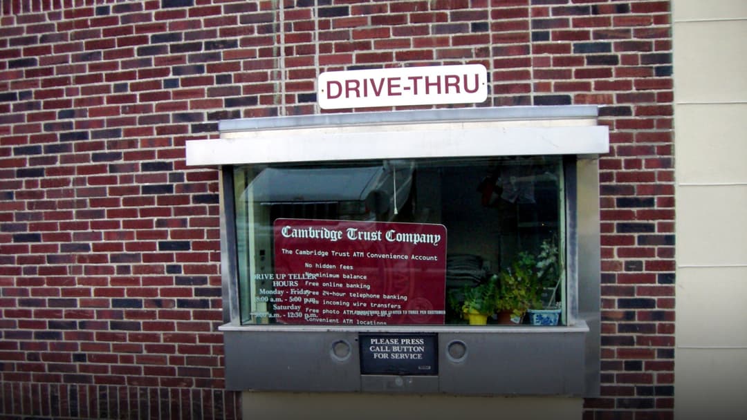 Automobile at a drive-thru bank teller window lane.