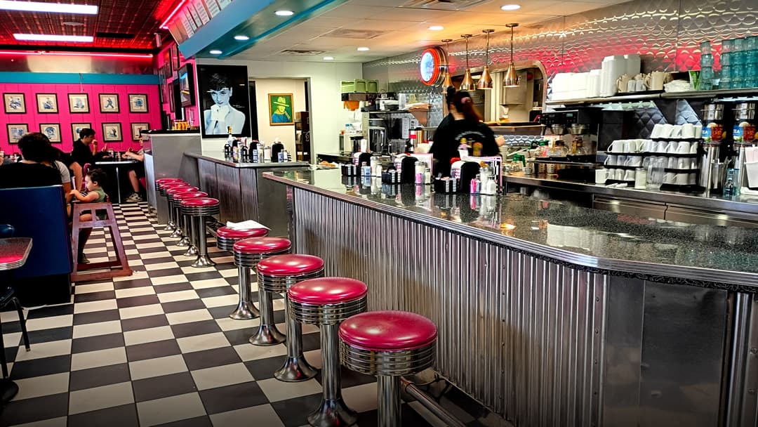 Interior of a classic American diner with neon signs and booths along Route 66.