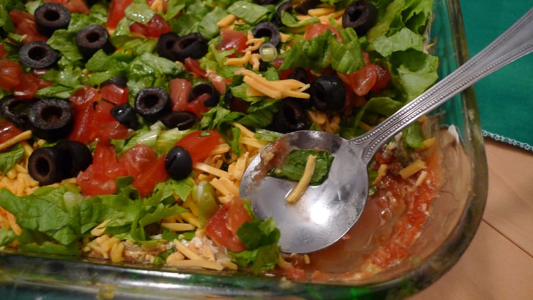 Seven-layer dip dish layered with beans, guacamole, cheese, and salsa