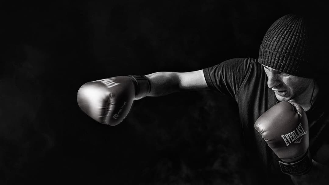 Landscape photograph of a boxer training in a dark ring under dramatic lighting