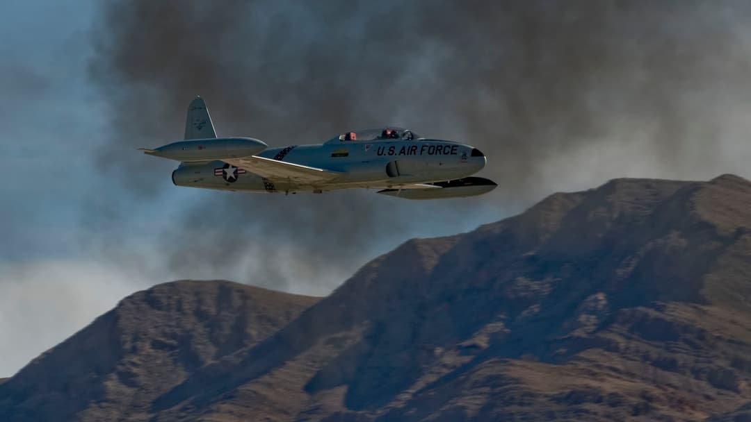 Silver Lockheed T-33 Shooting Star jet trainer flying at Aviation Nation airshow at Nellis Air Force Base