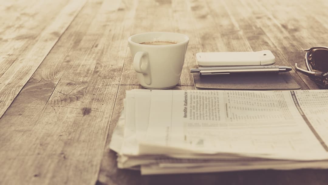 Coffee cup and smartphone resting on a wooden cafe table