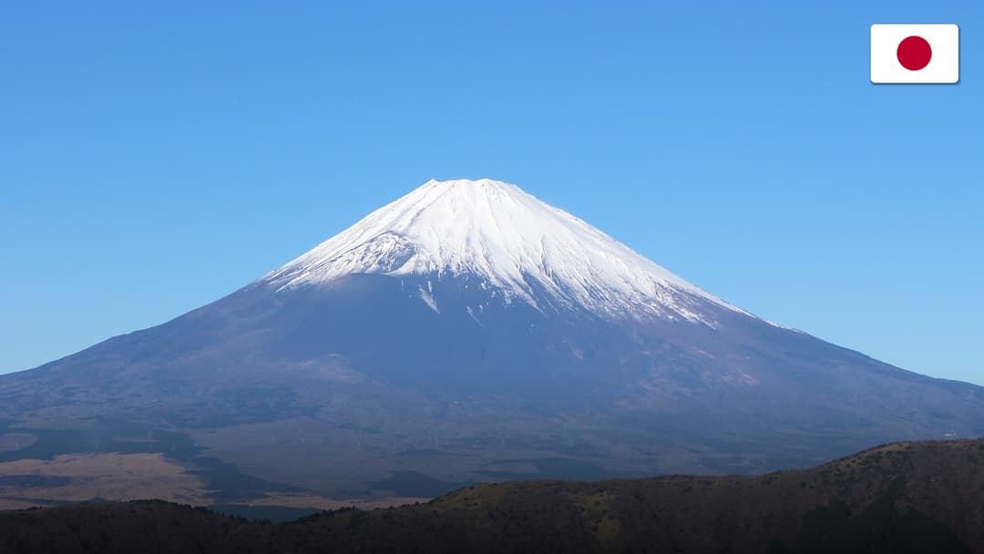 Red Chureito Pagoda framing the snow-capped peak of Mount Fuji during spring.