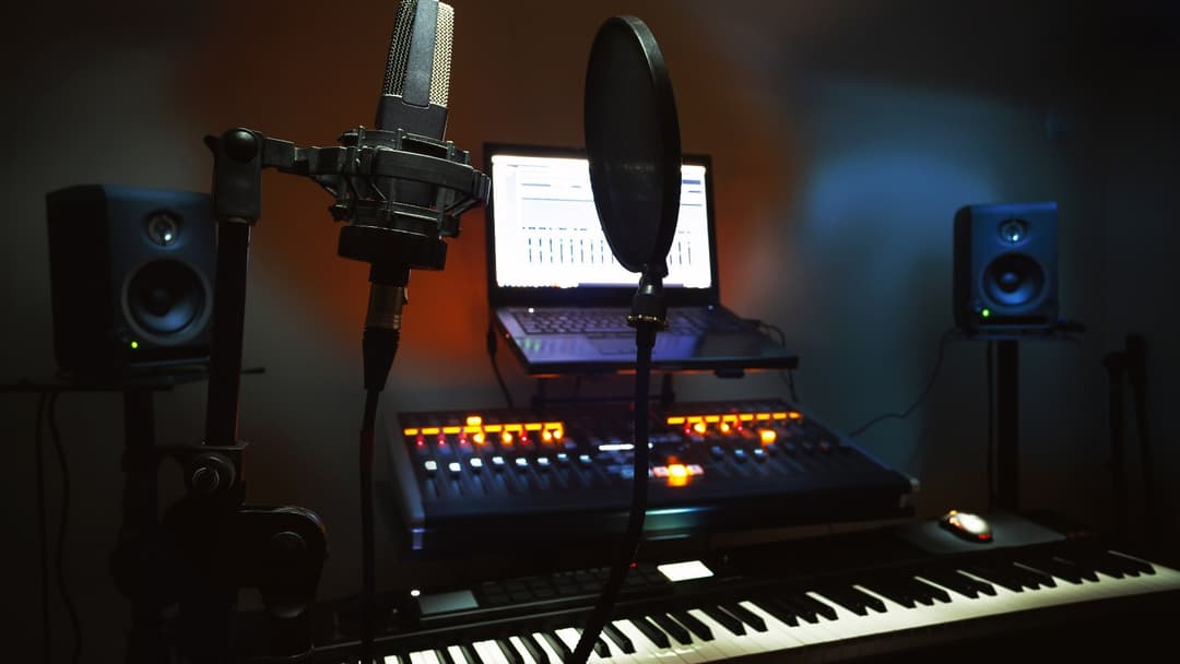 Recording studio condenser microphone, pop filter, MIDI keyboard, and mixing console