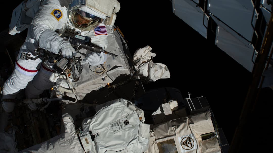 NASA astronaut Chris Williams operating a mechanical pistol grip tool during an orbital spacewalk