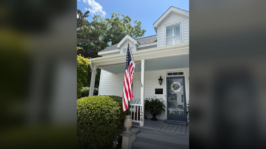 American flag hanging from the front porch railing of a charming residential house in Beaufort, North Carolina.