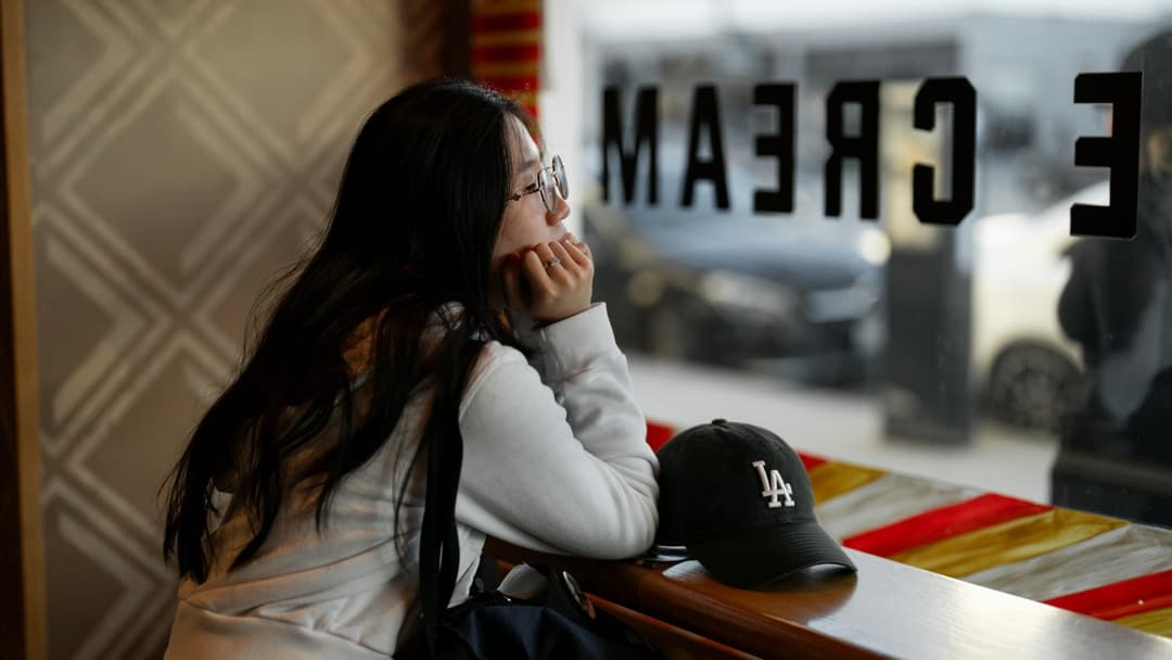 Woman resting her chin on her hand and gazing out a window during quiet downtime