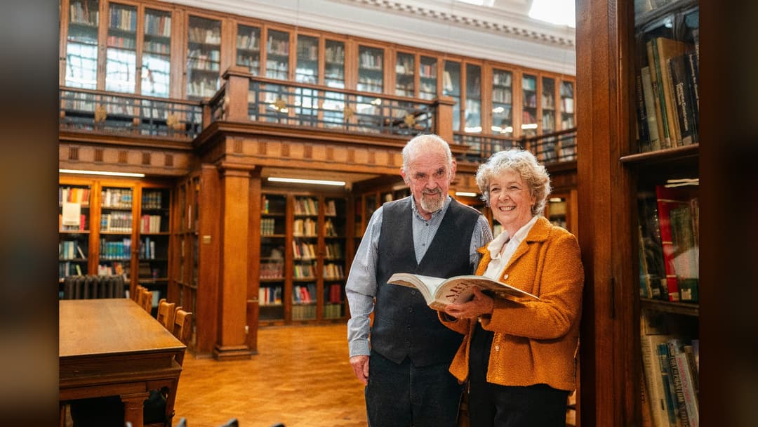 Older adult couple reading and engaged in active mental learning at a library.