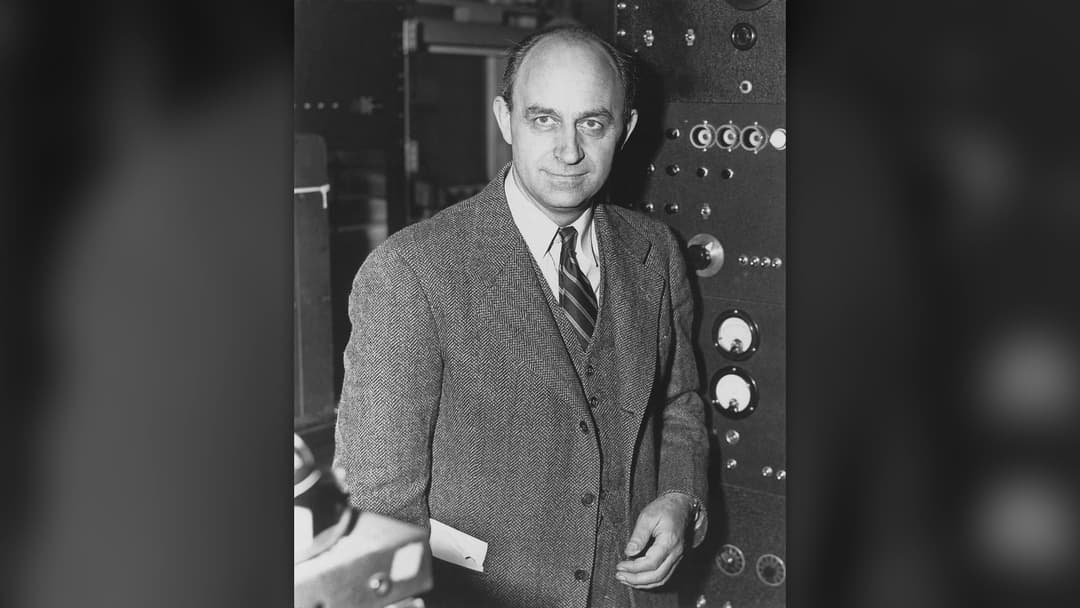 Physicist Enrico Fermi standing near nuclear research apparatus