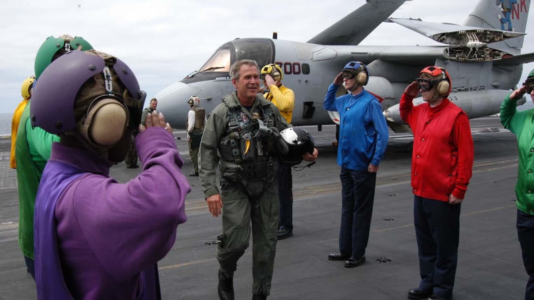 President George W. Bush in a flight suit saluting sailors aboard the aircraft carrier USS Abraham Lincoln in May 2003.