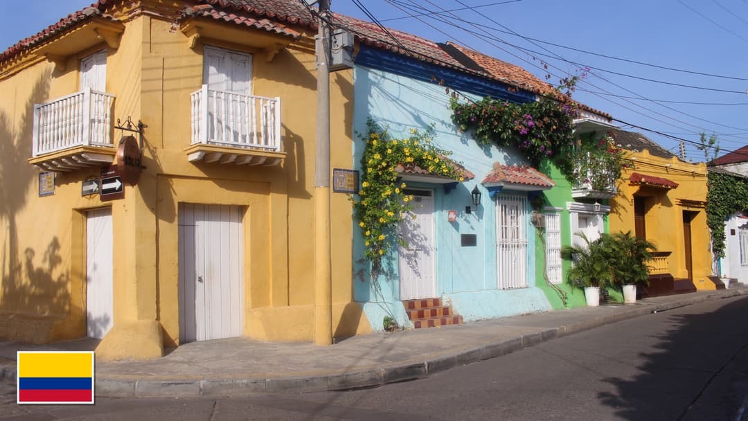 Colorful colonial street and flower balconies in Cartagena, Colombia with the Colombian flag in the bottom left corner