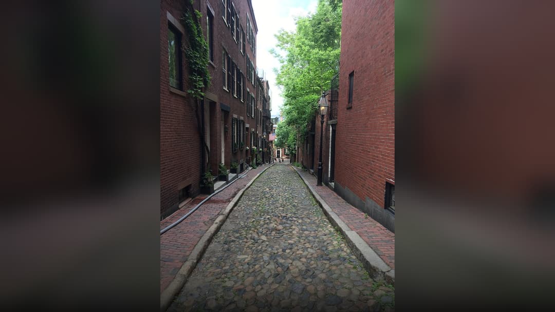 Picturesque cobblestone alley and brick townhomes on Acorn Street in Boston's Beacon Hill.