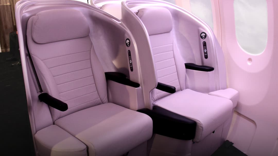 Passenger seating row in commercial airplane showing tight pitch between seat backs.