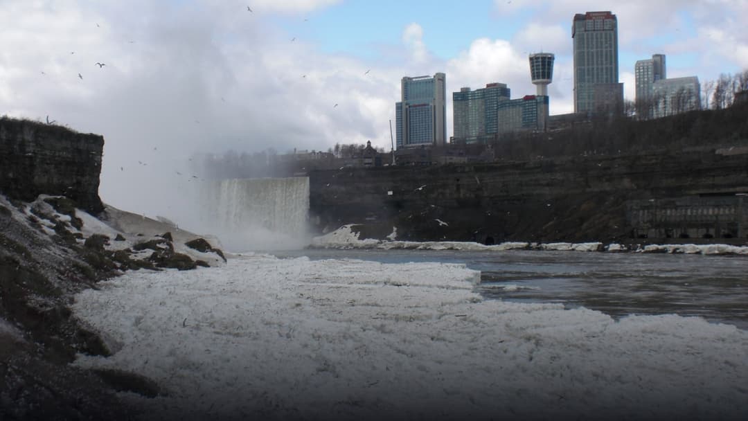 The frozen mist and massive snow drifts encasing the roaring Niagara Falls in winter.