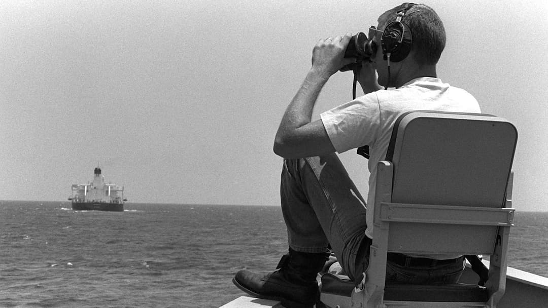 U.S. Navy lookout using binoculars to watch an escorted oil tanker during Operation Earnest Will in 1987.