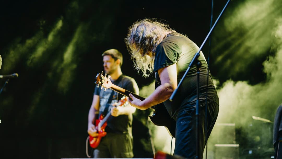 Rock band performing live on stage with arena lighting and cheering crowd