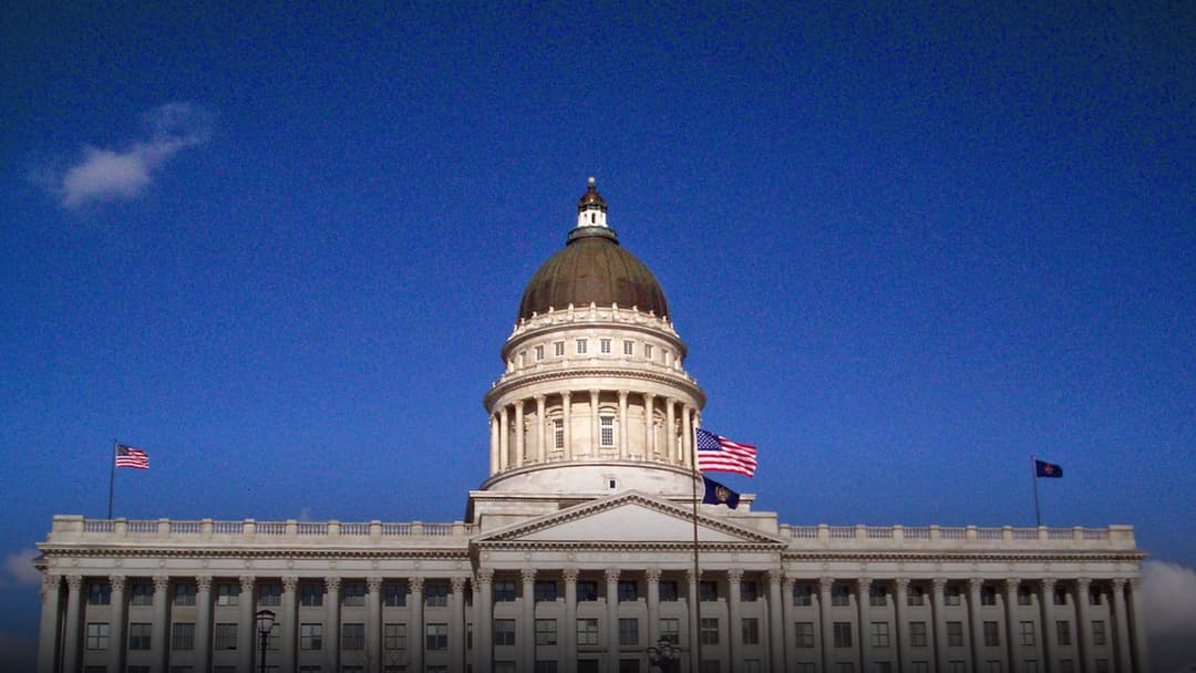 The Utah State Capitol in Salt Lake City framed by snow on the grounds and surrounding hills.