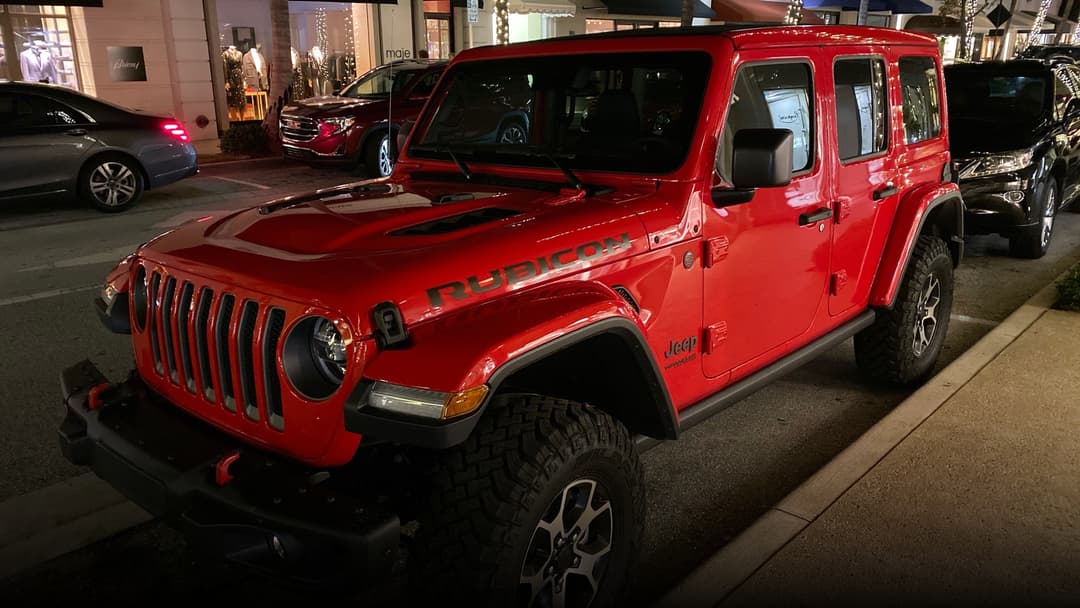 A vibrant red Jeep Wrangler Rubicon with iconic seven-slot front grille.