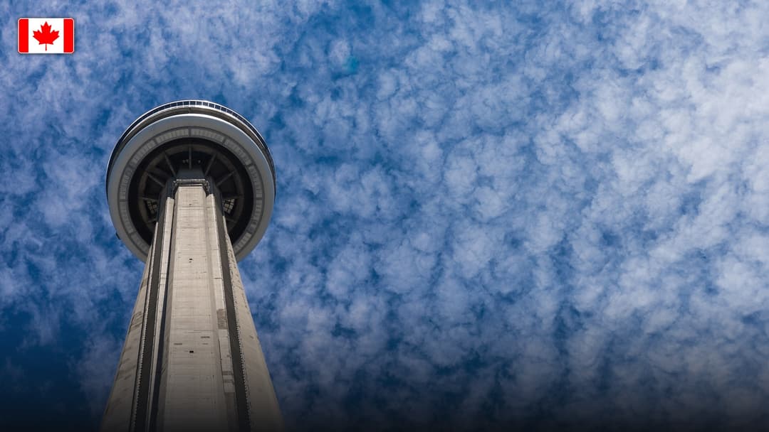 The CN Tower soaring over the modern skyline of Toronto, with the flag of Canada.