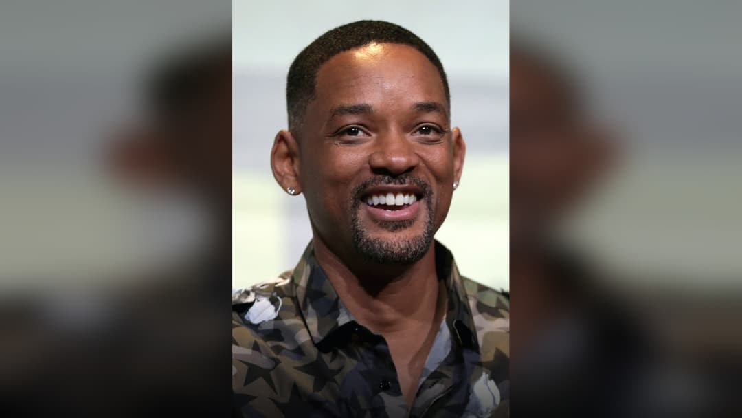 Will Smith waving on the red carpet.