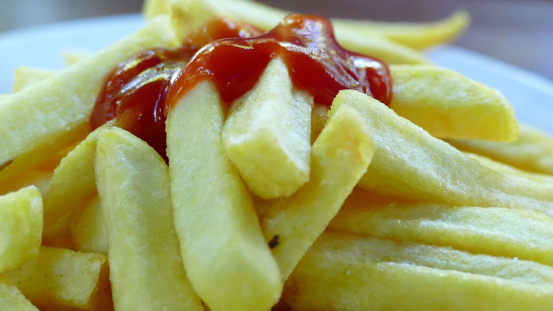 Crisp french fries in a metal serving basket with ketchup