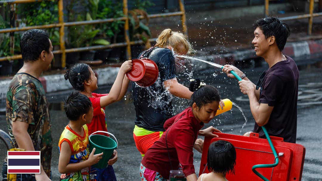Songkran New Year water festival celebration in Chiang Mai, Thailand with the Thai flag in the bottom left corner