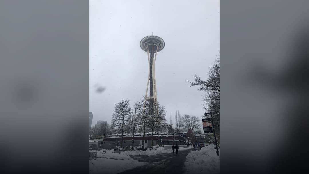 The Space Needle towering high into a gray winter sky amid a Seattle snowstorm.