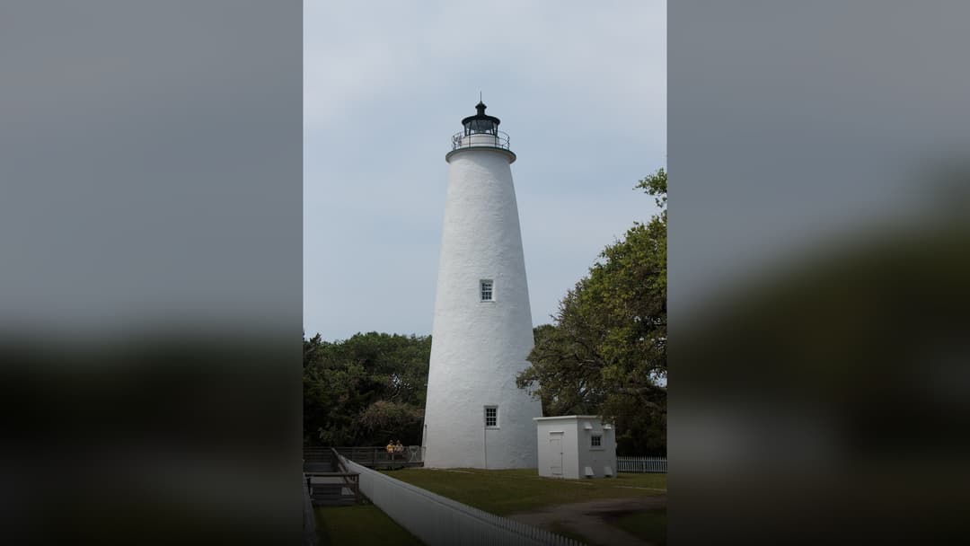 The historic whitewashed Ocracoke Island Lighthouse under a clear coastal blue sky.