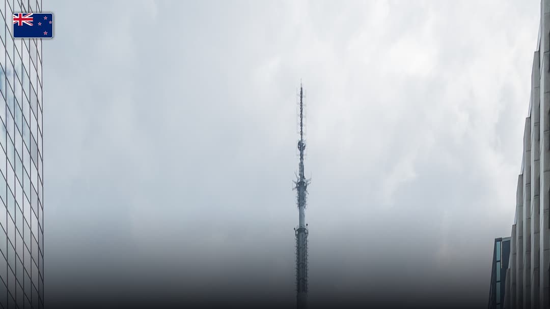 The Sky Tower rising high above the Auckland cityscape, with the flag of New Zealand.