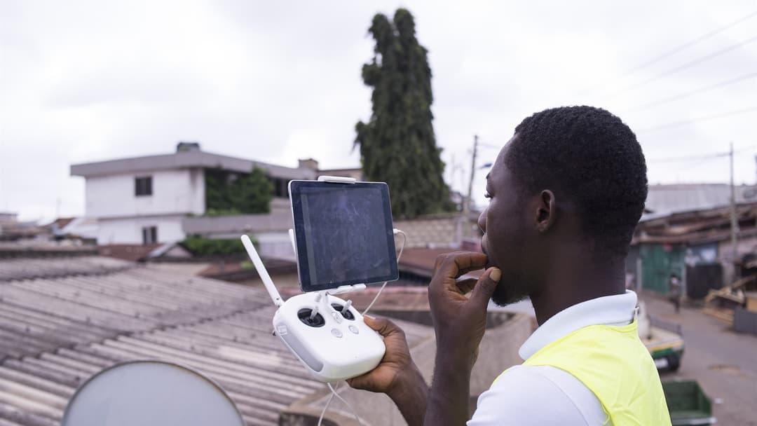 Commercial drone pilot operating a remote controller with a live tablet telemetry screen