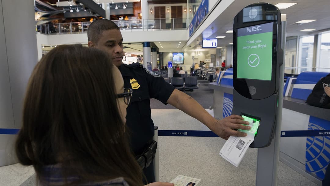 Officer inspecting a biometric facial recognition verification kiosk at Houston International Airport