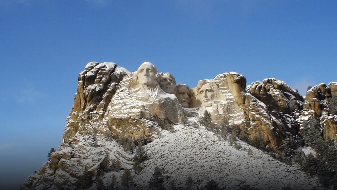 The presidential faces of Mount Rushmore carved into stone and dusted in fresh white snow.