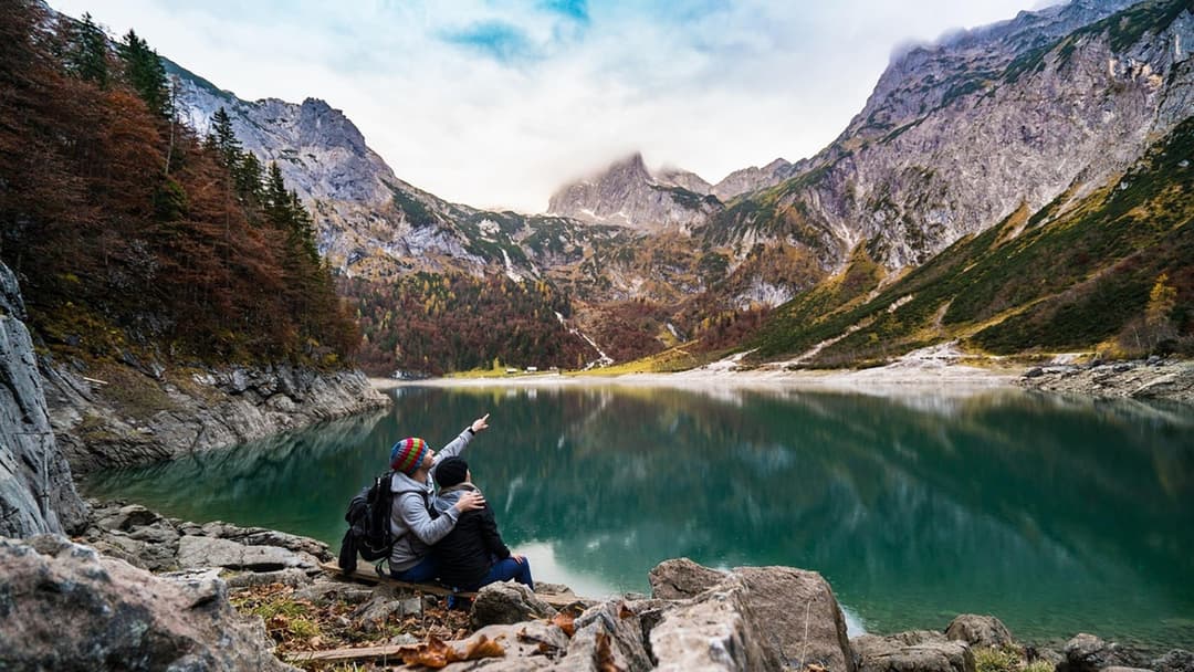 Couple hiking together by a mountain lake under open outdoor sunlight