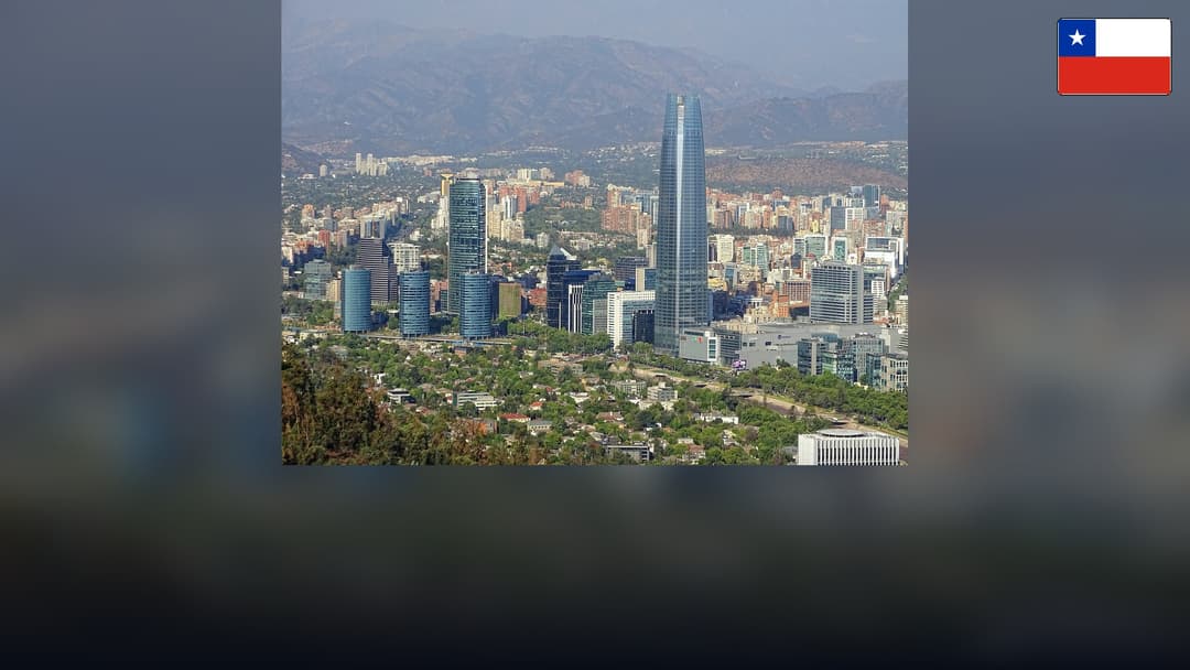 Gran Torre Santiago skyline with the Andes mountains and the Chilean flag in the top right corner.