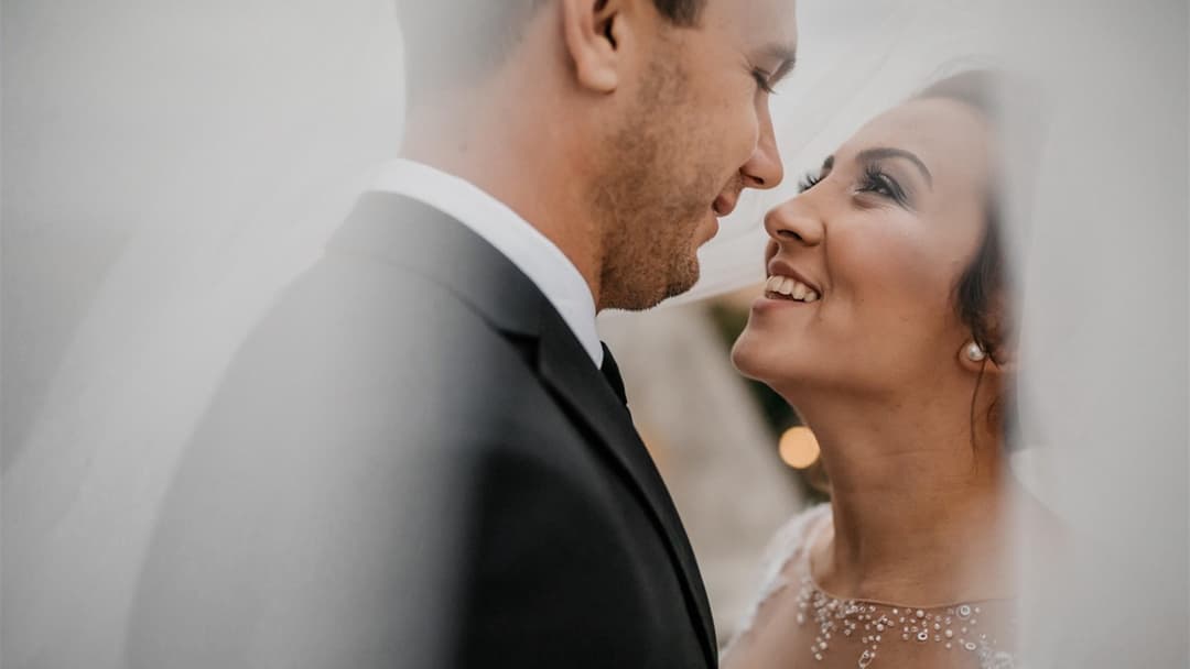 Bride and groom smiling closely at each other on their wedding day