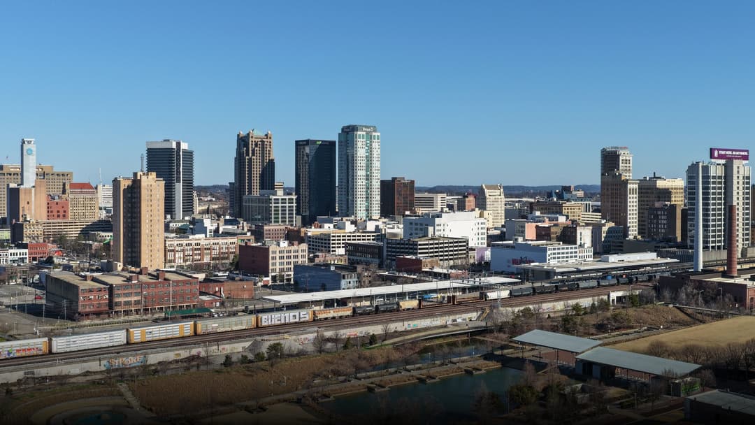 Panoramic view of downtown Birmingham Alabama skyline surrounded by lush green hills.