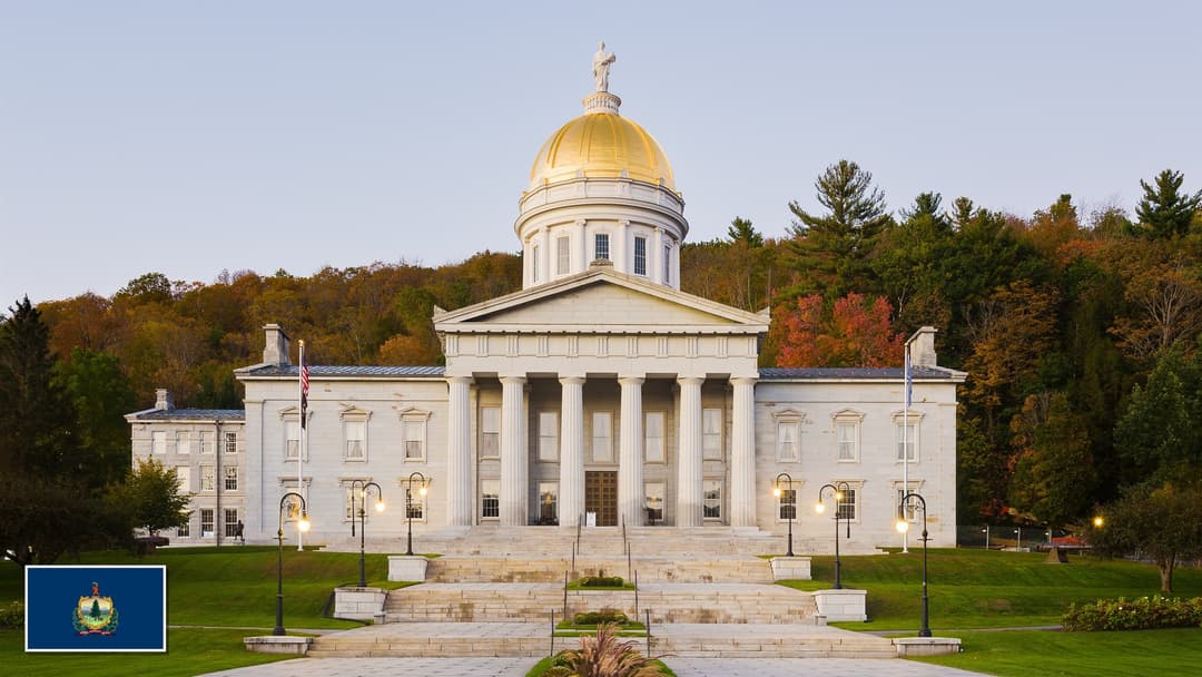 Vermont State House in Montpelier, Vermont with the Vermont state flag in the bottom left corner