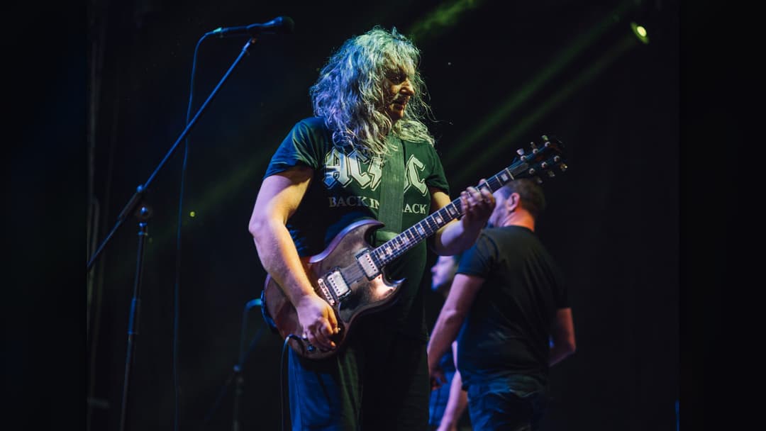 Musician performing live on stage with electric guitar