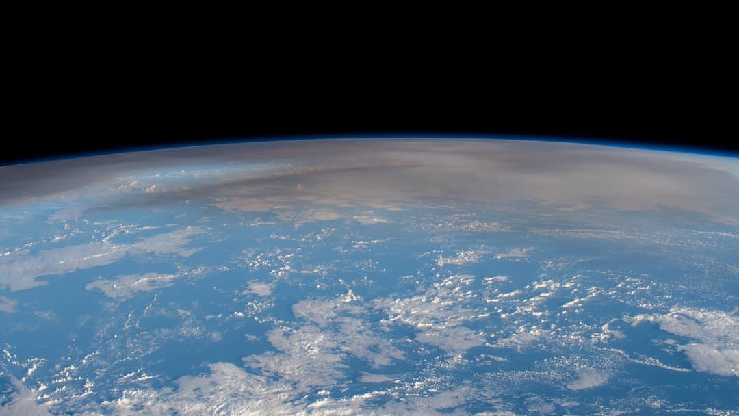 Orbital view from the International Space Station showing the giant umbrella ash plume of Hunga Tonga over the Pacific Ocean.