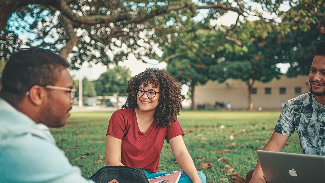University students from a shared community and demographic background smiling together on campus lawn