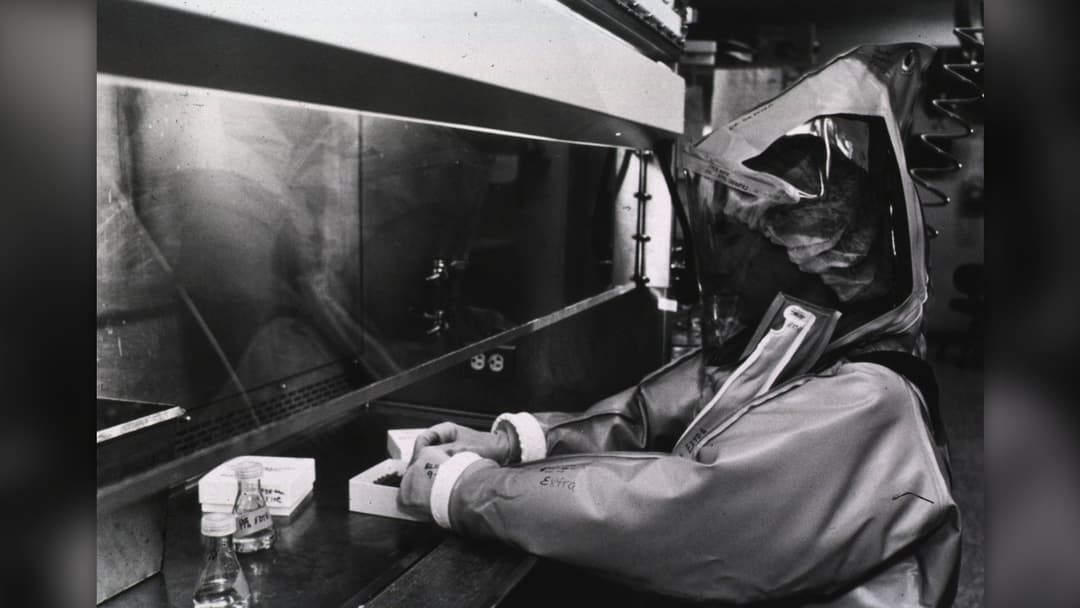 A scientific researcher working inside a high-level biological containment virology laboratory.