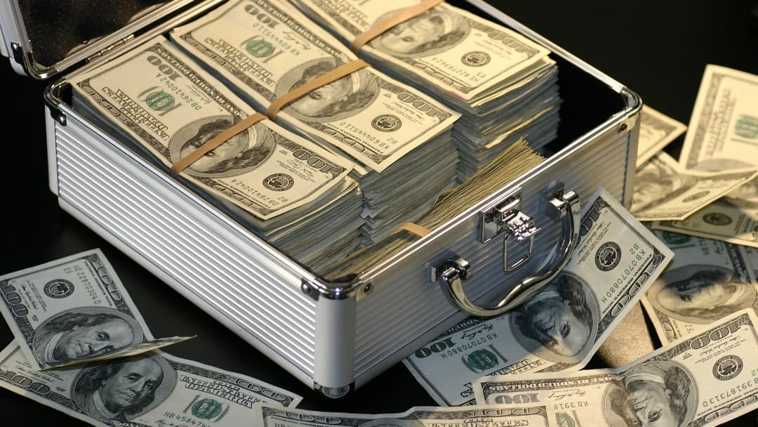 Briefcase filled with bundled stacks of US hundred-dollar bills and cash notes.