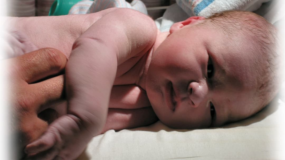 Newborn infant resting safely inside a hospital maternity bassinet.