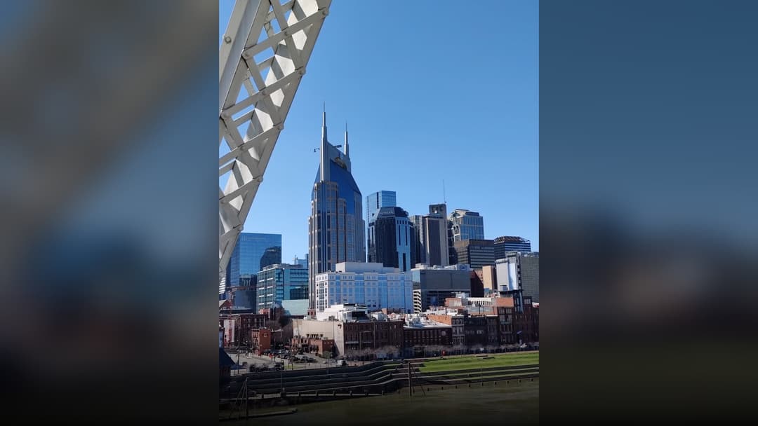 Downtown Nashville Tennessee skyline and pedestrian bridge across the Cumberland River at dusk.