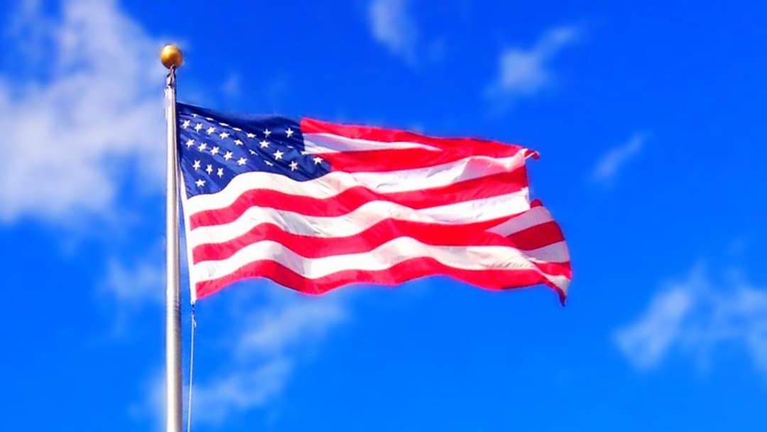 American 50-star flag waving against blue sky