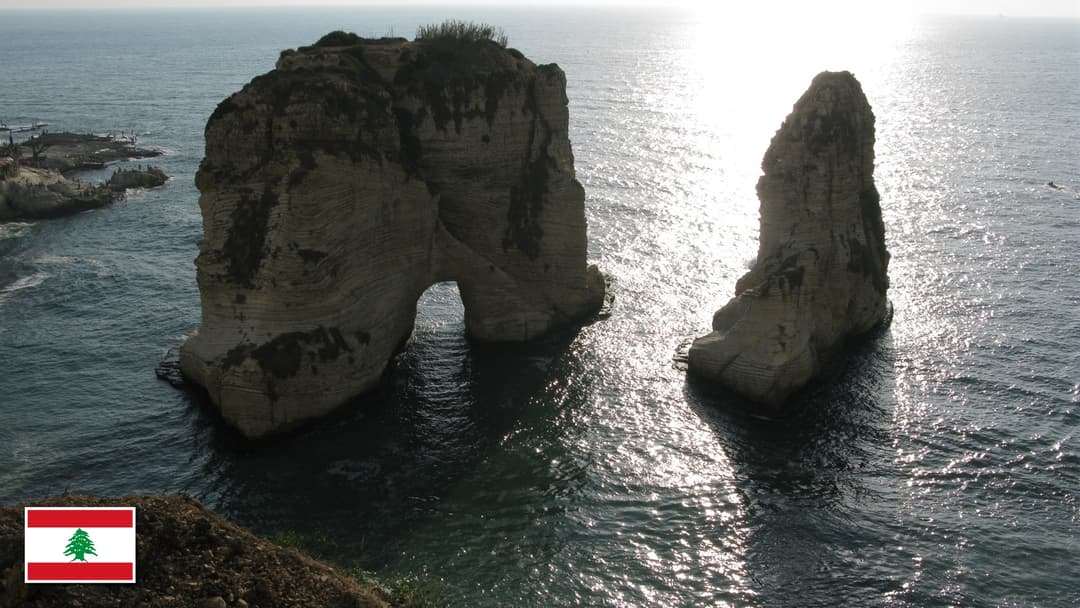Pigeon Rocks of Raouche on the Mediterranean coast in Beirut, Lebanon with the Lebanese flag in the bottom left corner